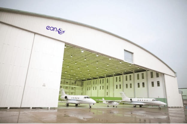 EAN Aviation’s hangar with its doors drawn back, two business jets and a light aircraft parked inside.