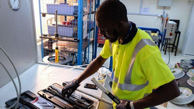 An EAN engineer in a high-visibility vest working on aircraft components at a bench in the maintenance workshop.