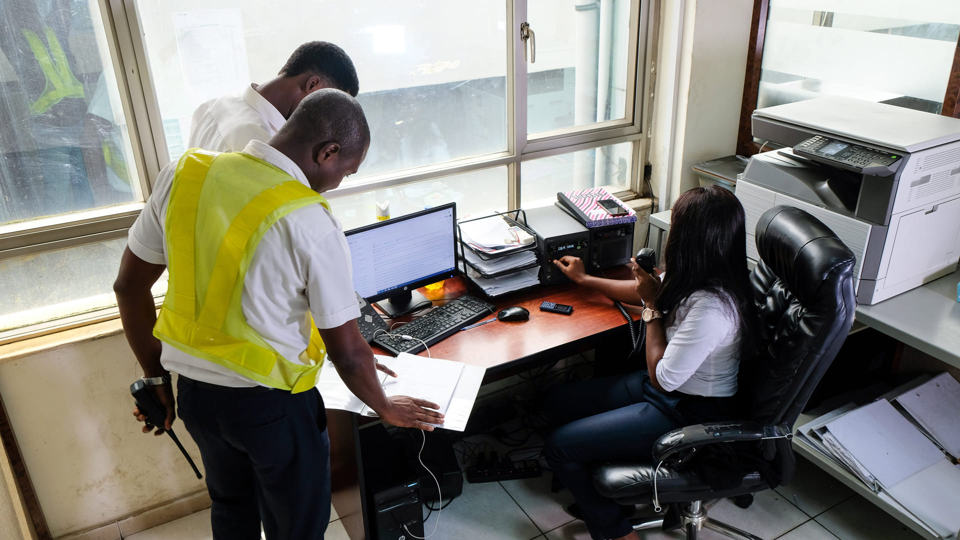 EAN operations staff working a radio and reviewing paperwork at a desk overlooking the ramp.